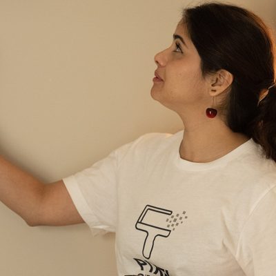 Professional cleaner reaching up to dust shelf